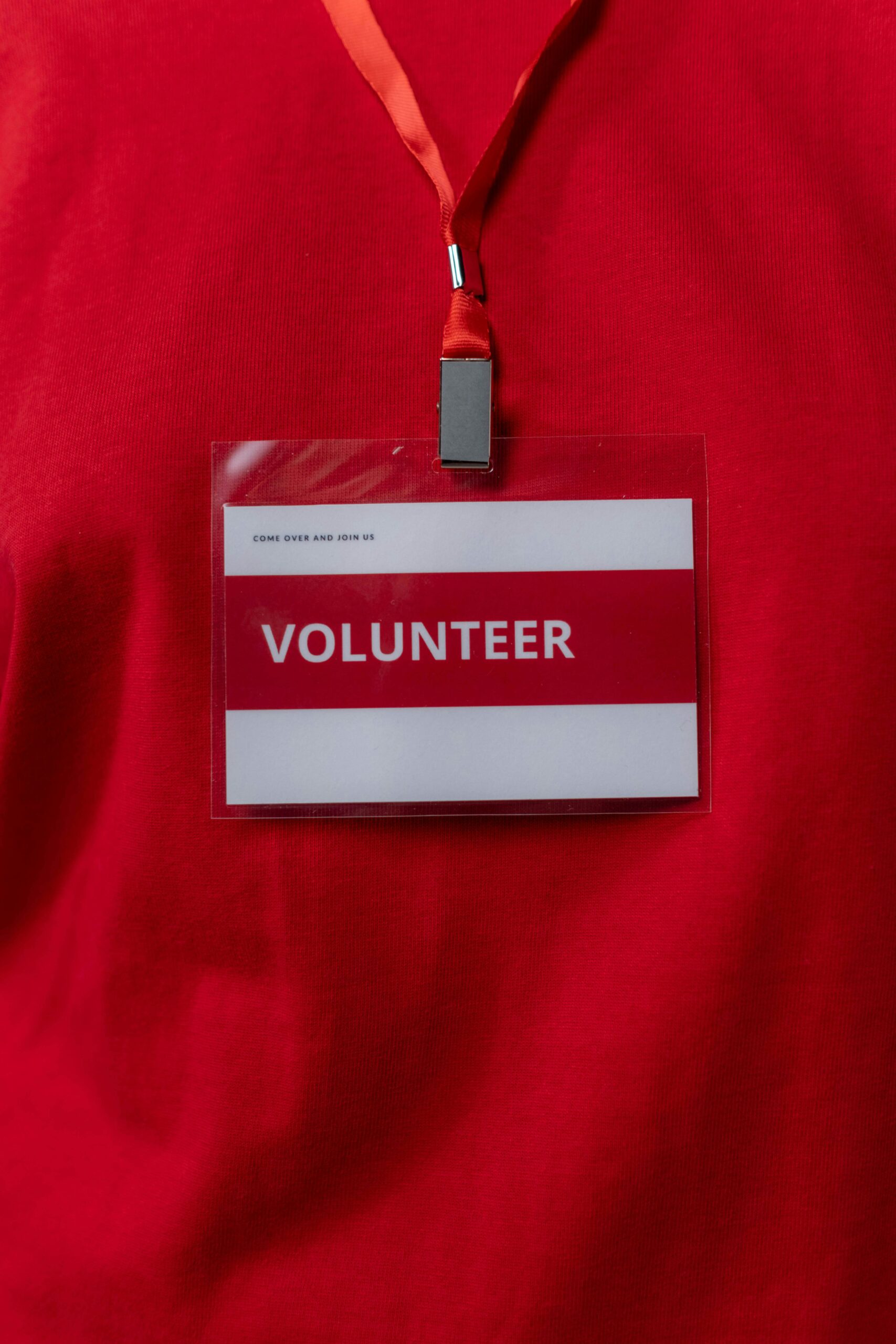 Home A close-up of a volunteer name tag hanging on a red lanyard, symbolizing community service.