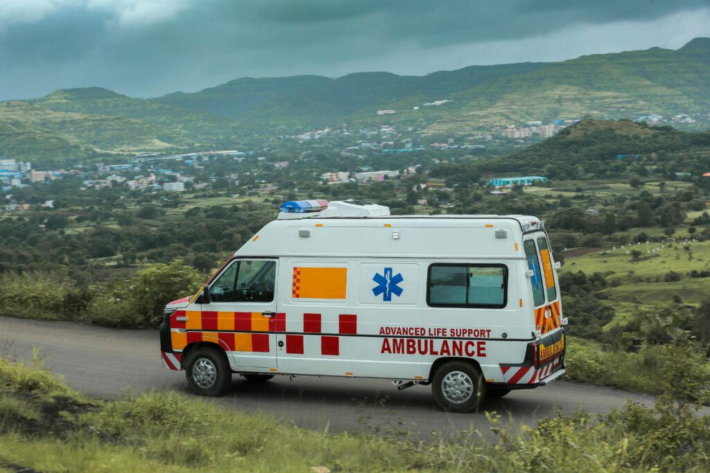 pranayama Advanced life support ambulance driving on a scenic road in Pune, India with lush green hills in the background.